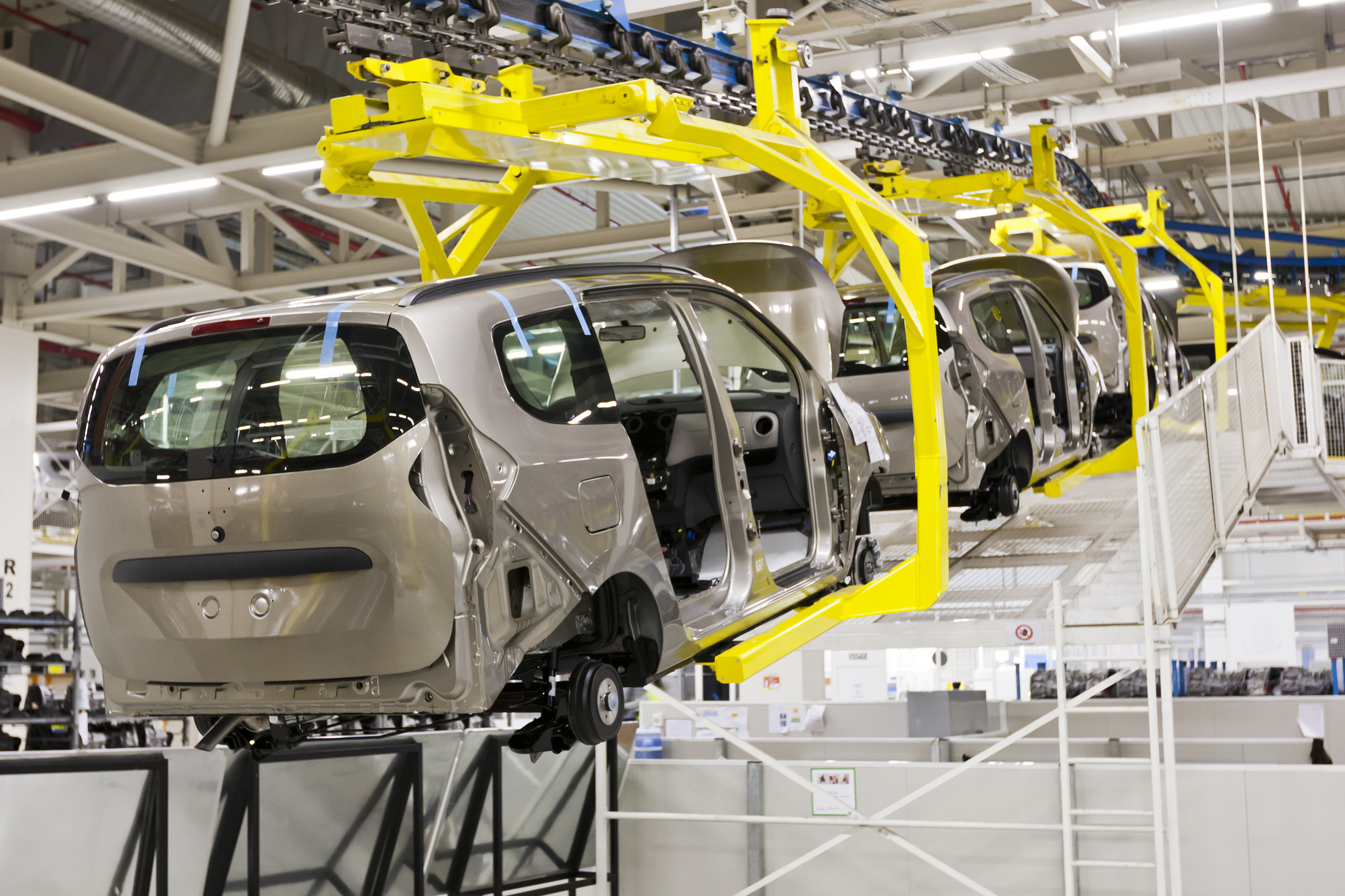multiple cars shown hanging from assembly line