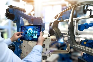 Person holding smart handheld device near car assembly line