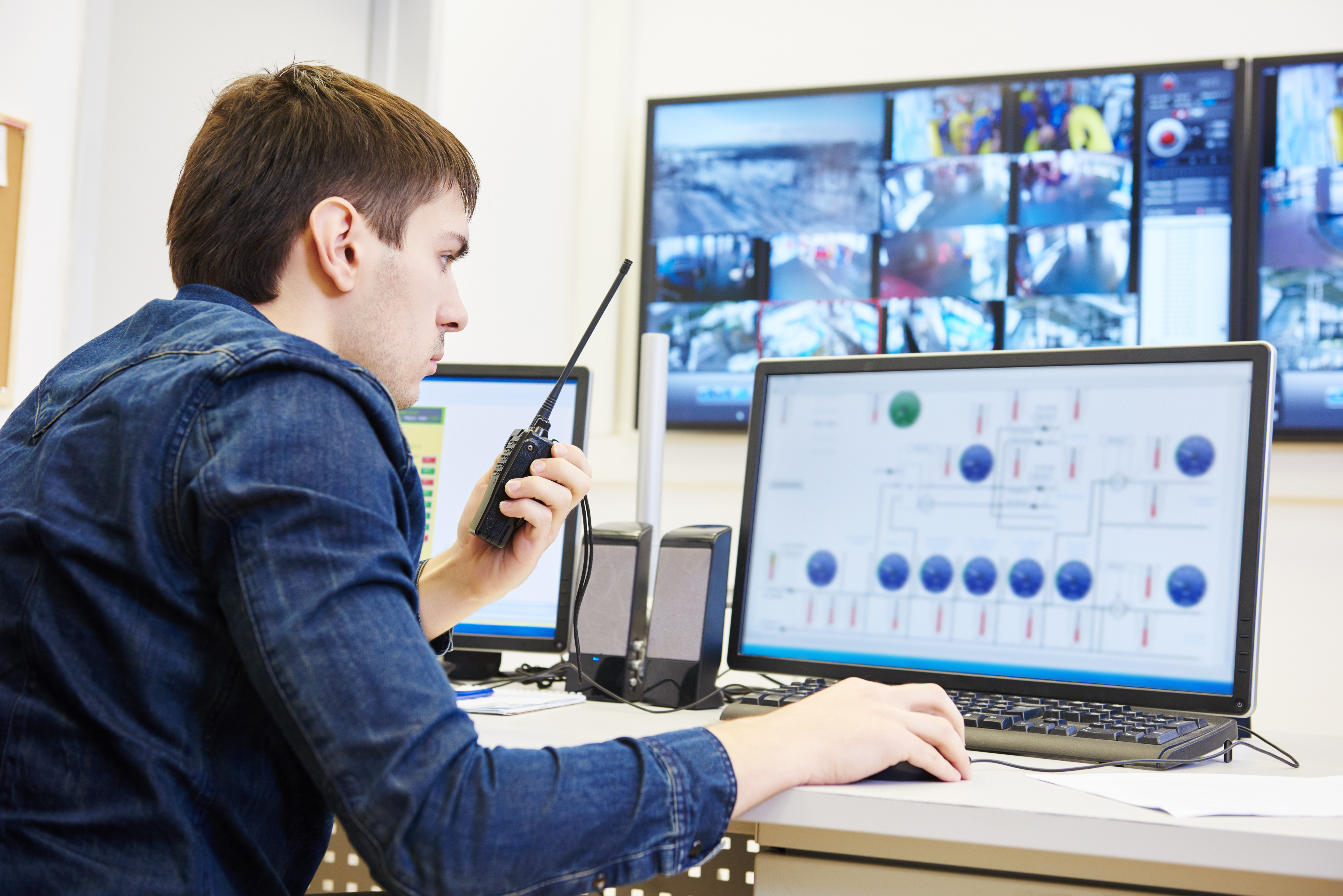 Control center technician monitoring operations & communicating via two-way radio.