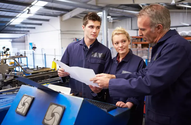 Workers Reviewing Blueprints with Industrial Equipment