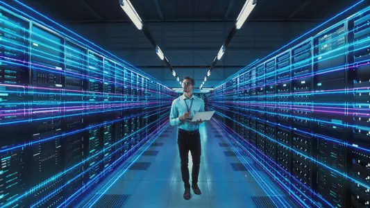 futuristic concept: data center chief technology officer holding laptop, standing in warehouse, information digitalization lines streaming through servers. saas, cloud computing, online service