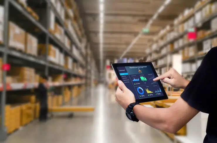 Système de gestion d'entrepôt intelligent. Mains d'un travailleur tenant une tablette avec un entrepôt flou en arrière-plan