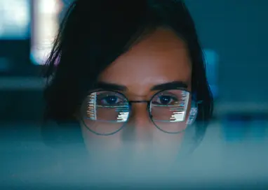 Closeup of Female computer programmer works on complex software development tasks at her home office late into the night. Software developer, artificial intelligence and programming.