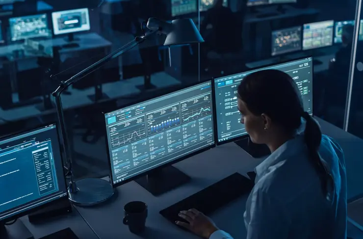 Femme ingénieur logiciel travaillant dans un bureau de surveillance moderne avec flux d’analyse en direct avec des graphiques sur un grand écran numérique. Salle de surveillance Les scientifiques et les gestionnaires du Big Data sont assis devant des ordinateurs.