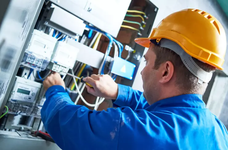 Cable technician in protective apparel working on networking panel setup