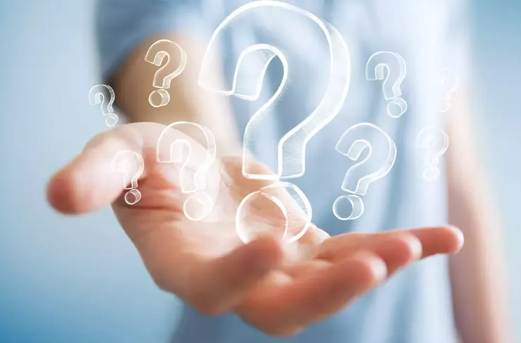 Businessman on blurred background holding hand drawn question marks