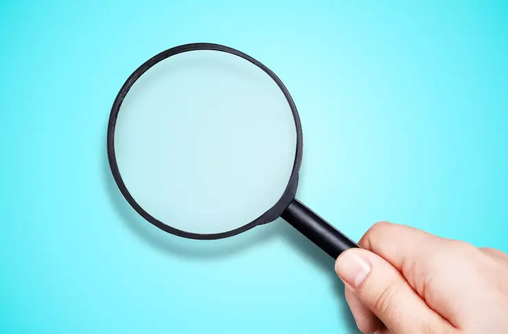 black magnifier in hand on blue background, search concept