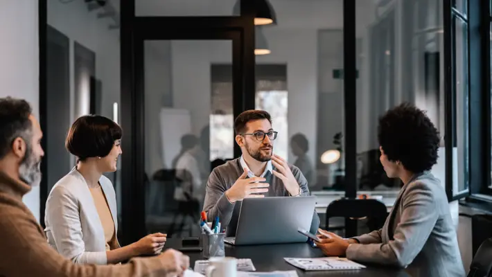 A dedicated mentor is explaining mentees importance of project while sitting at the boardroom in corporate firm.