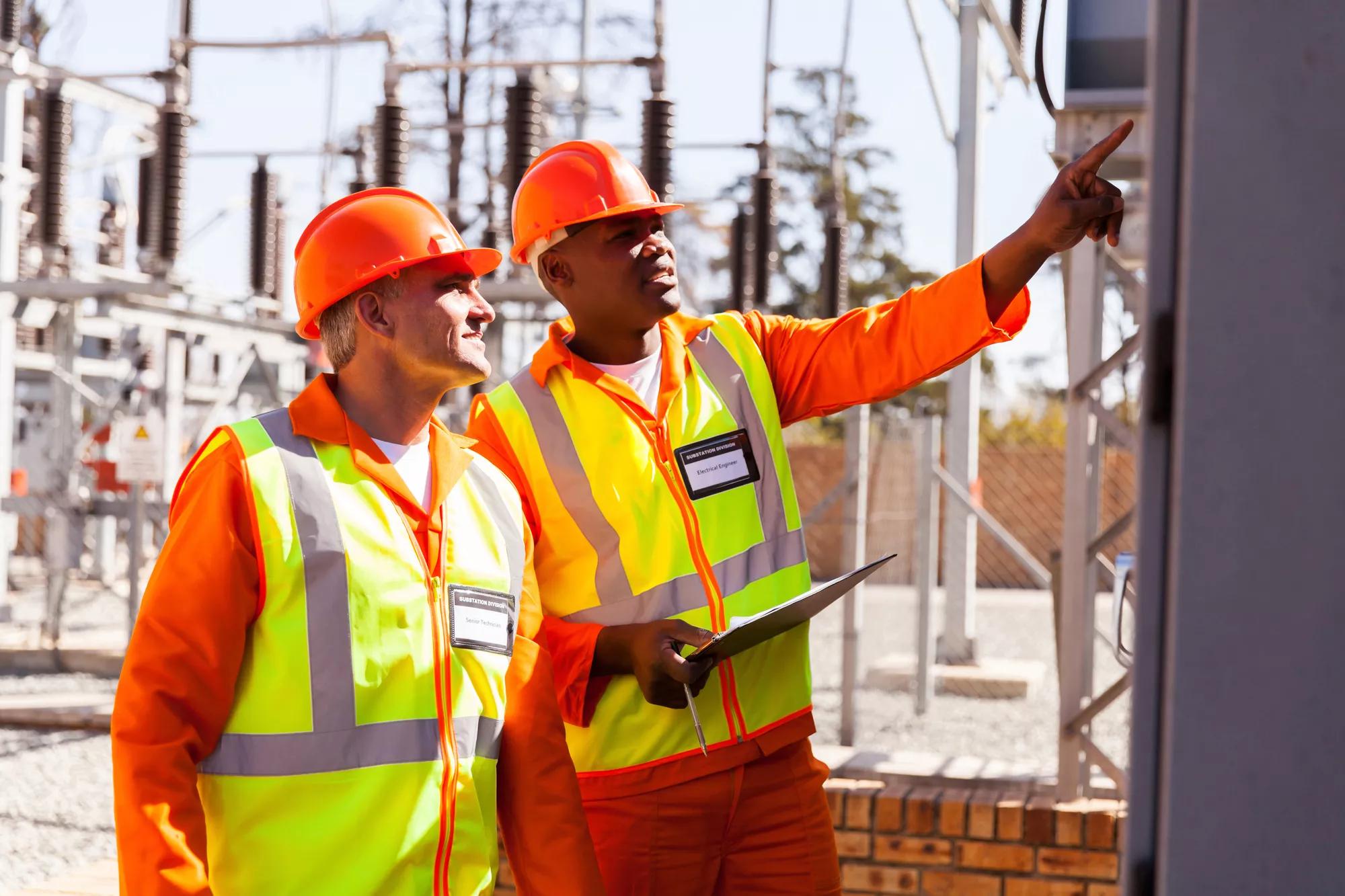 successful electrical engineers taking machine readings in substation