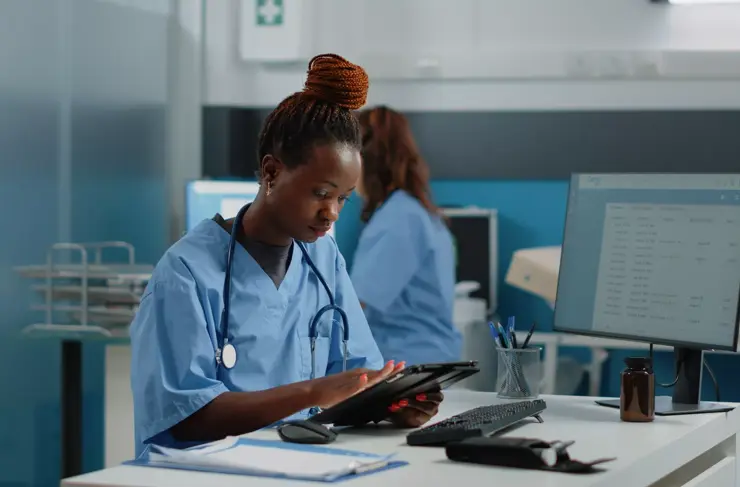 African american nurse holding digital tablet for checkup visit in doctors office. Black woman working as medical assistant, using device with touch screen for healthcare and medicine.