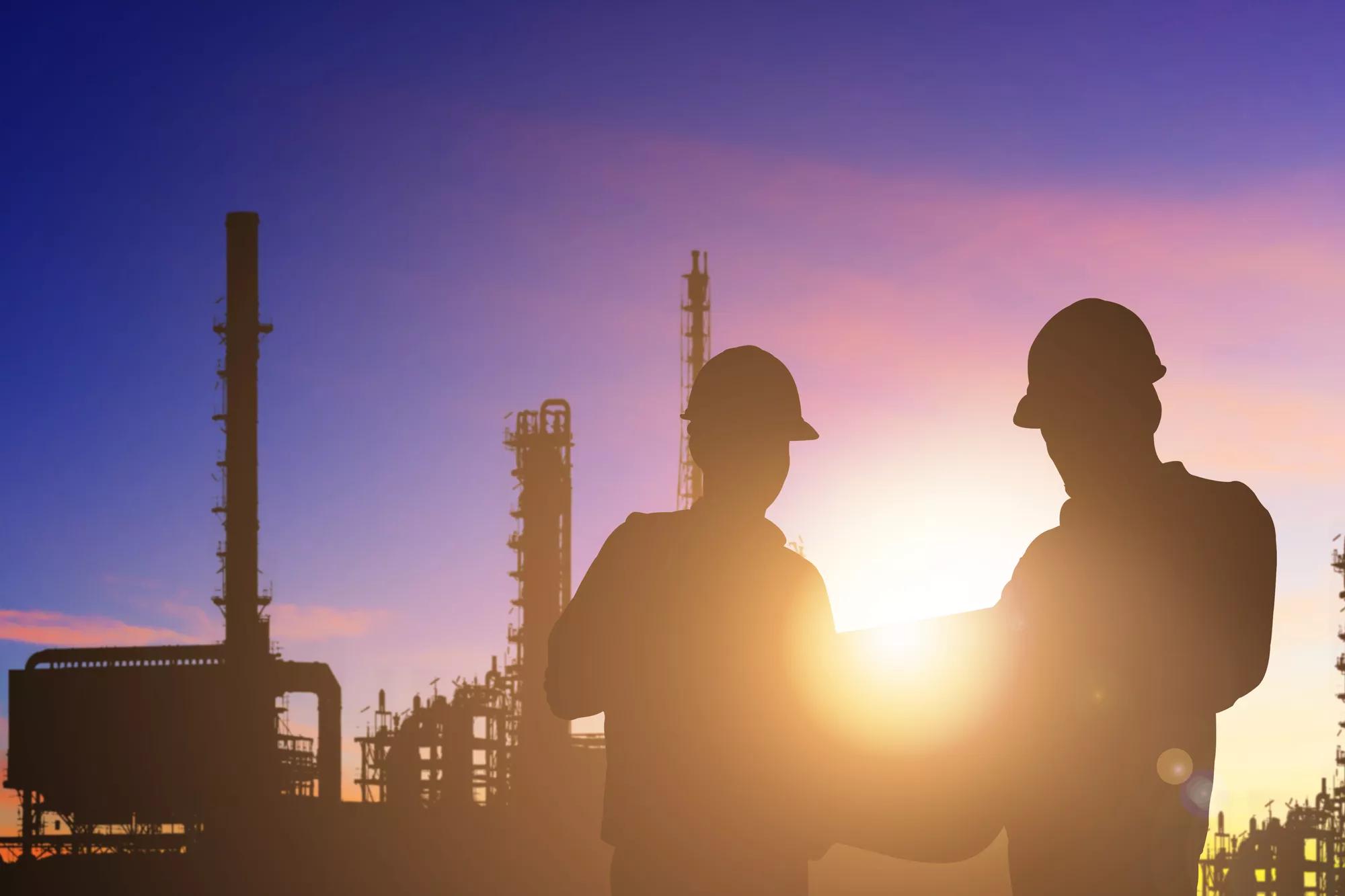 Silhouette of engineer and foreman working at petrochemical oil refinery in sunrise