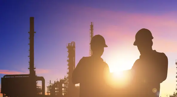 Silhouette of engineer and foreman working at petrochemical oil refinery in sunrise