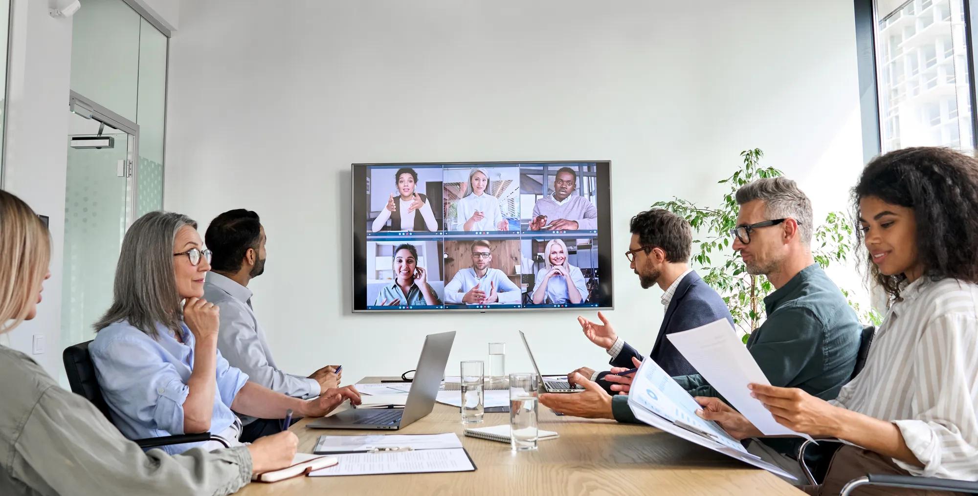 Mitarbeiter eines Unternehmens in einer Online-Videokonferenz mit einem Fernsehbildschirm im Konferenzraum eines Vorstands. Videokonferenz-Präsentation, globales virtuelles Schulungskonzept für Gruppen in Unternehmen.