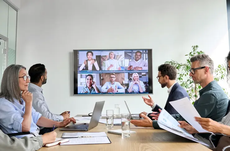 Diverse company employees having online business conference video call on tv screen monitor in board meeting room. Videoconference presentation, global virtual group corporate training concept.