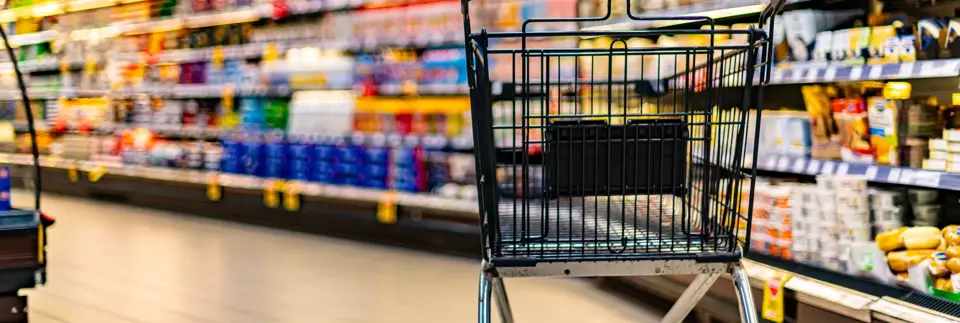 a shopping cart by a store shelf in a supermarket