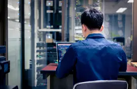 Ingenieur, der an einem Laptop in einer Rechenzentrumsumgebung mit Schaltschränken und Gestellen arbeitet