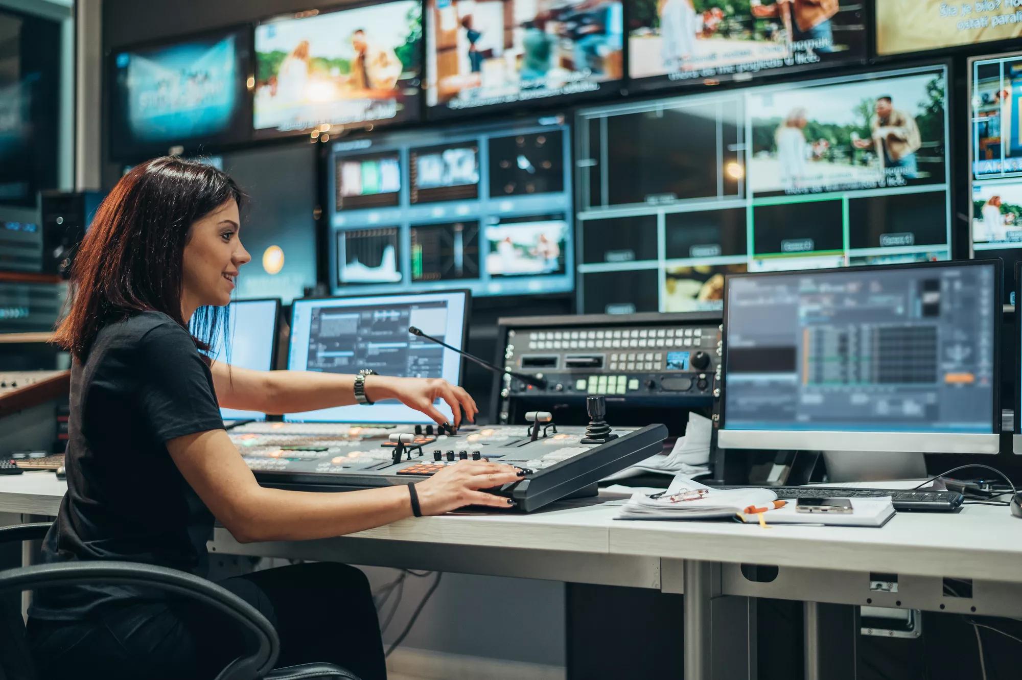 Jeune femme belle travaillant dans une salle de contrôle de diffusion sur une chaîne de télévision