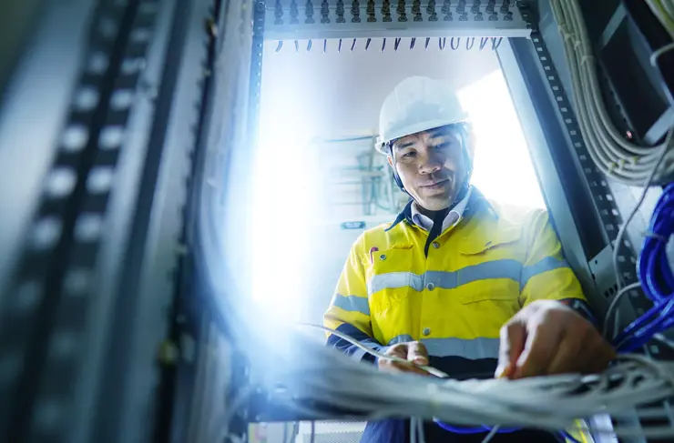 Engineer in yellow uniform, wearing a white safety helmet, checking communication system, big data concept.