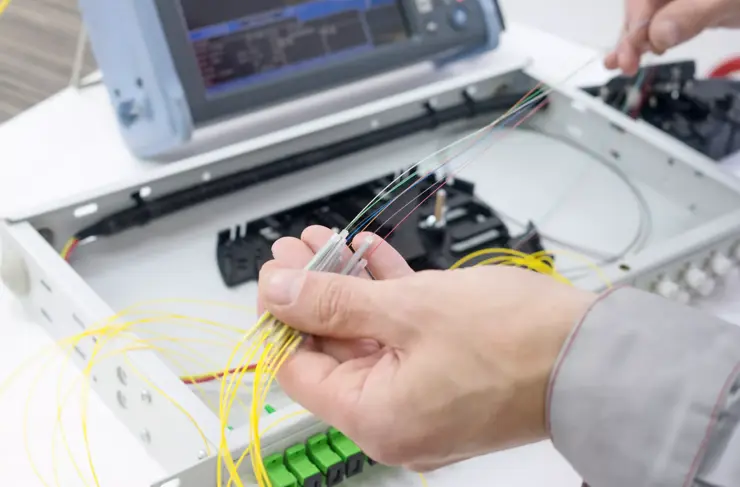épissage du câble à fibre optique sur le plateau d’épices avec les mains des travailleurs