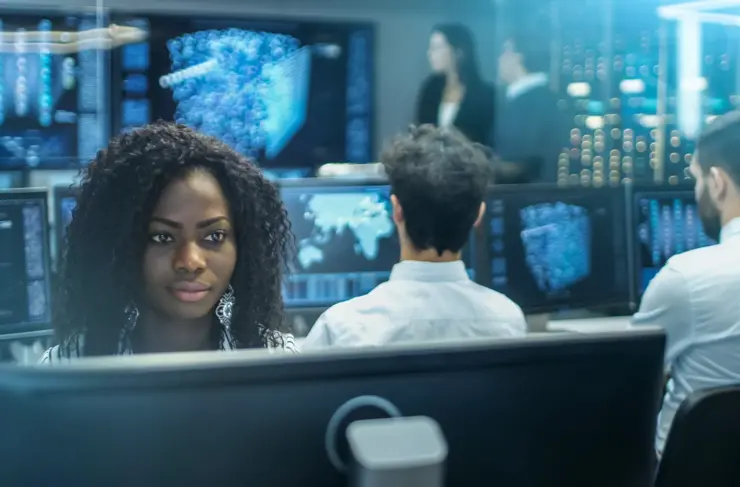 Female Computer Engineer Works on a Neural Network/ Artificial Intelligence Project with Her Multi-Ethnic Team of Specialist. Office Has Multiple Screens Showing 3D Visualization.
