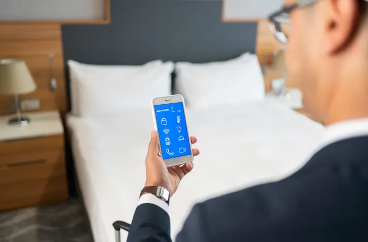 Businessman Using Smart Room Application On Smartphone screen İn Hotel Room