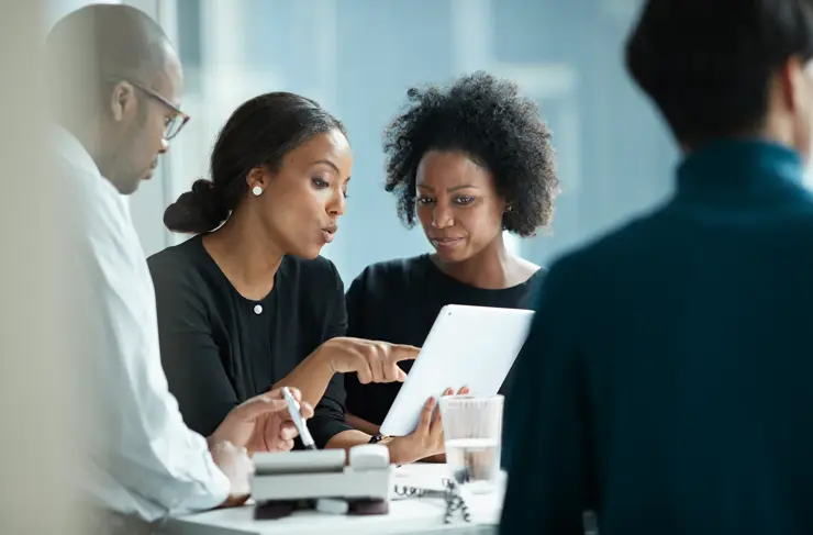 group of co-workers standing around desk and having meeting