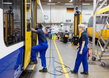 Des ingénieurs ferroviaires inspectent une rame de train dans un atelier de maintenance.