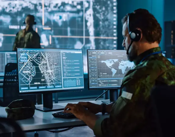 Military Surveillance Officer Working on a City Tracking Operation in a Central Office Hub for Cyber Control and Monitoring for Managing National Security, Technology and Army Communications.