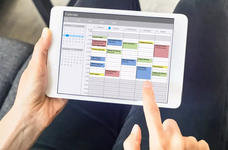 Calendar app on tablet computer with planning of the week with appointments, events, tasks, and meeting. Hands holding device, time management concept, organization of working hours planner, schedule
