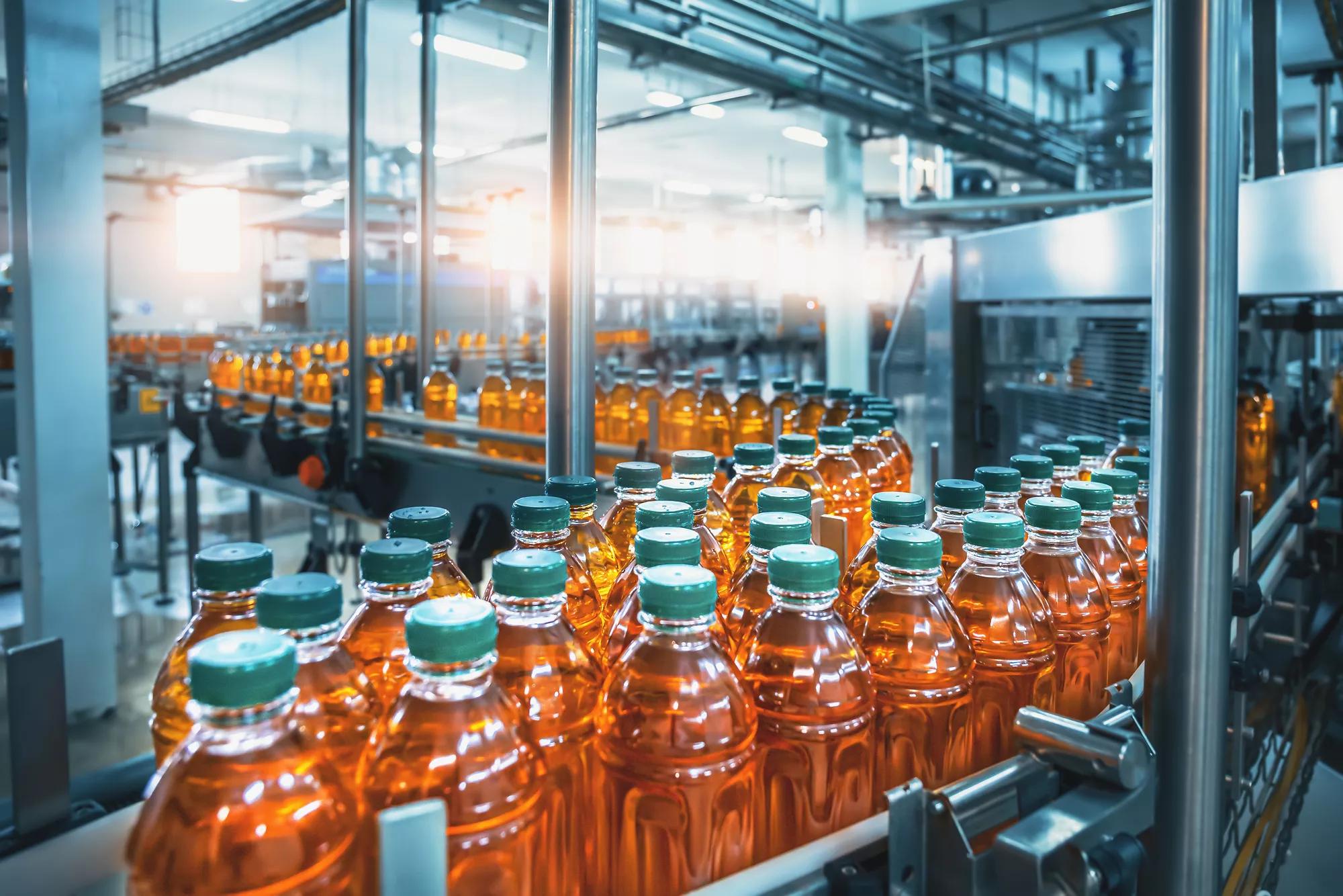 Tapis roulant, jus en bouteilles, intérieur d’usine de boissons de couleur bleue, ligne de production industrielle.