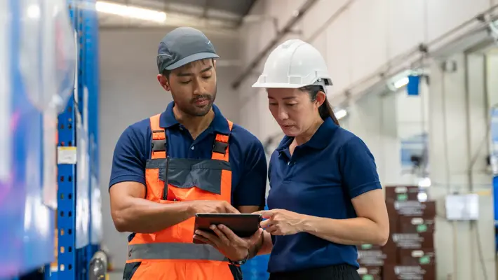 Warehouse worker and manager checks stock and inventory with digital tablet.