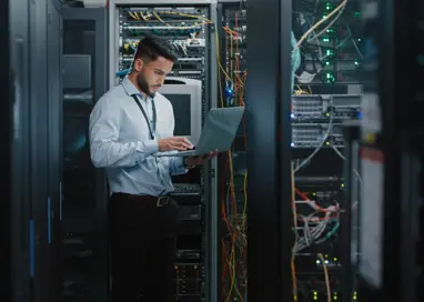 Shot of a young male engineer using his laptop in a server room
