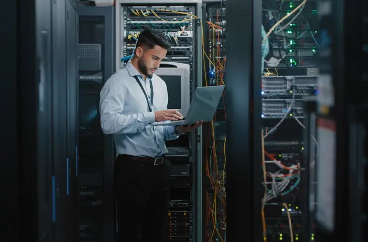 shot of a young male engineer using his laptop in a server room