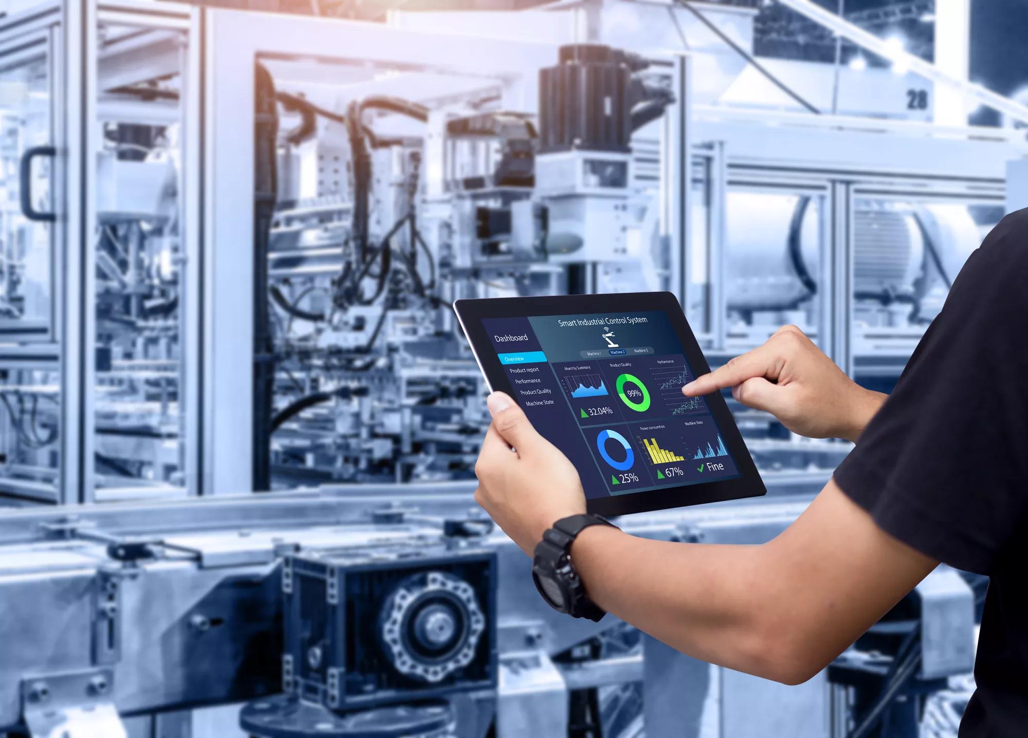 Smart industry control concept.Hands holding tablet on blurred automation machine as background