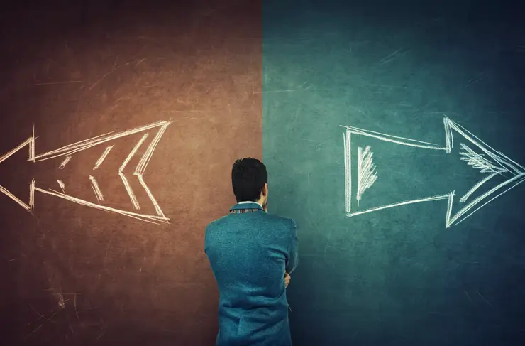 Puzzled businessman and a split blackboard with arrows going in two different ways red and blue side. Correct choice between left and right, failure or success. Difficult decision and doubt concept.