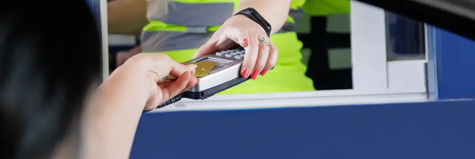 unrecognizable woman paying with a bank card at a pos of an operator, also unrecognizable, of a toll road