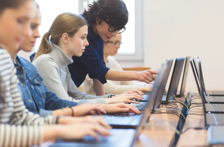 female students learning computer programming with teacher