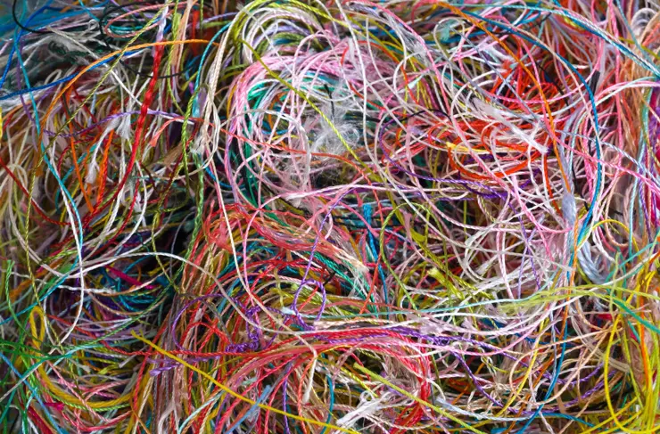 Multi-colored tangled threads abstract texture pattern background. Macro shot of colorful needlecraft silk thread ropes. Colored natural thread pile for sewing clothe scattered randomly like spaghetti