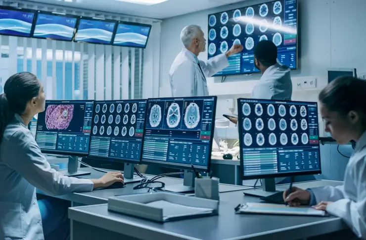 Une équipe de scientifiques professionnels travaille au Laboratoire de recherche sur le cerveau. Neurologues/neuroscientifiques entourés de moniteurs montrant des tomodensitométries et des IRM, ayant des discussions et travaillant sur des ordinateurs personnels.