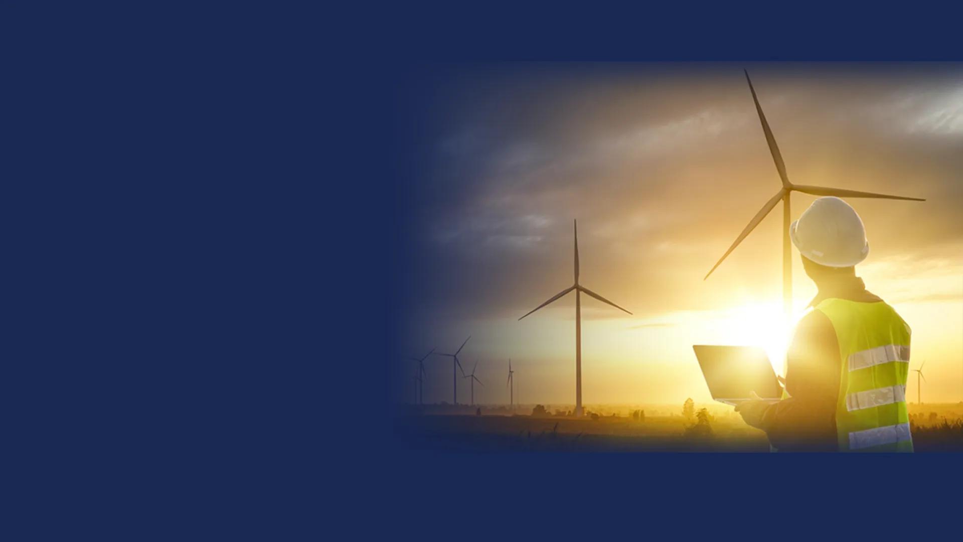 man working on computer on wind mill farm