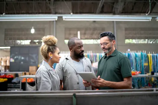 Manager zeigt seinen Mitarbeitern in einer Fabrik etwas auf einem digitalen Tablet