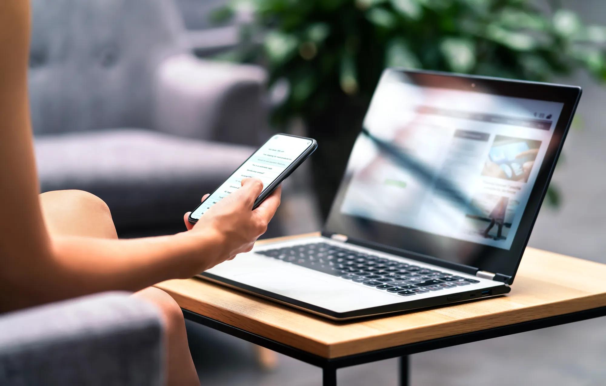 Wireless wifi for remote work in airport lounge bar, hotel lobby or cafe. Phone and laptop. Woman using smartphone and modern notebook pc computer on table.