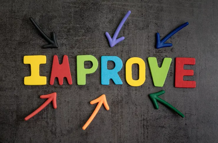 Self improvement concept by multiple arrow pointing to colorful alphabet IMPROVE at the center on dark black cement wall background.