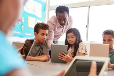 elementary teacher working through learning activity with children using tablets