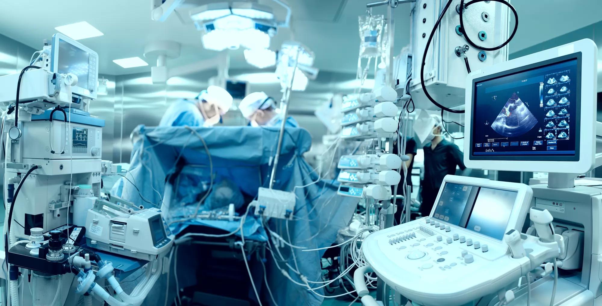 In advanced operating room with lots of equipment, patient and working surgical specialists