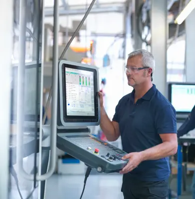 Engineers at lathe controls in factory