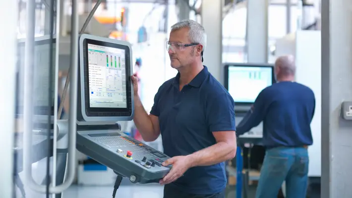 Engineers at lathe controls in factory