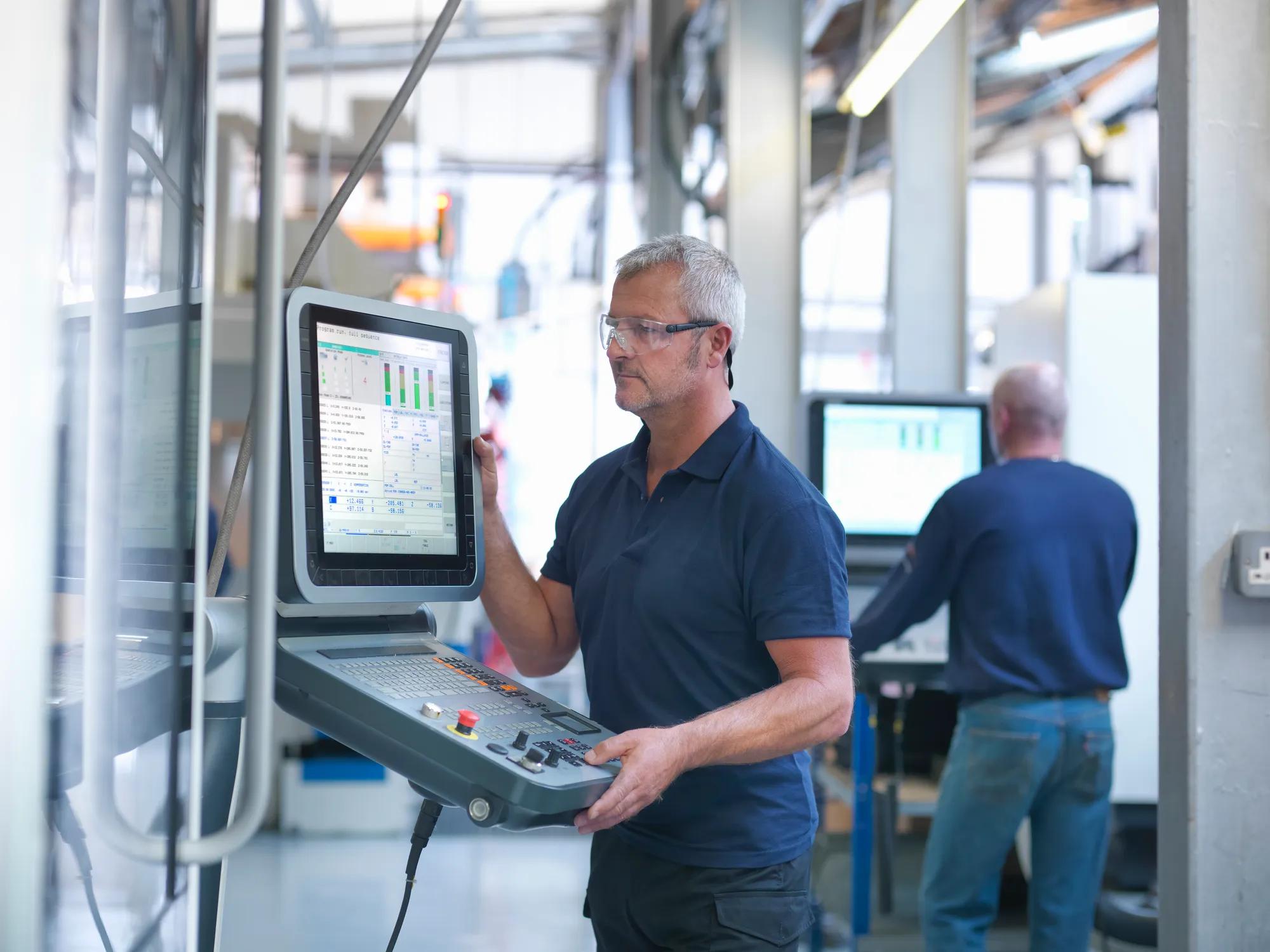 Engineers at lathe controls in factory