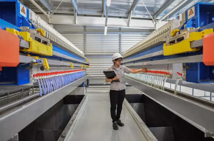 Jeune ingénieure mécanique vérifiant et essayant le fonctionnement du nouveau réglage de la machine de la station d’épuration, des filtres et du transport par pipeline des eaux usées dans l’usine