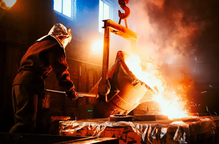 Workers operates at the metallurgical plant. The liquid metal is poured into molds. Worker controlling metal melting in furnaces.